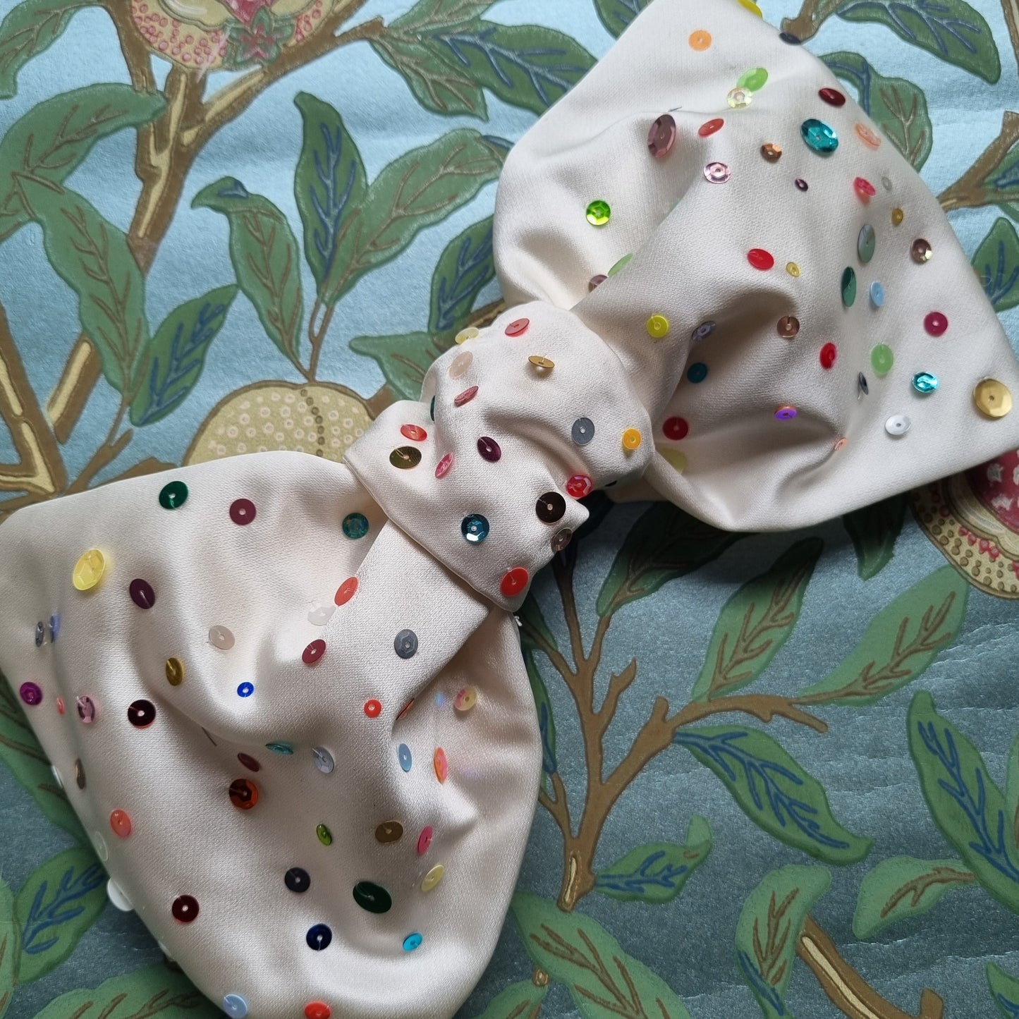 A white silk bow with multi coloured sequins scattered