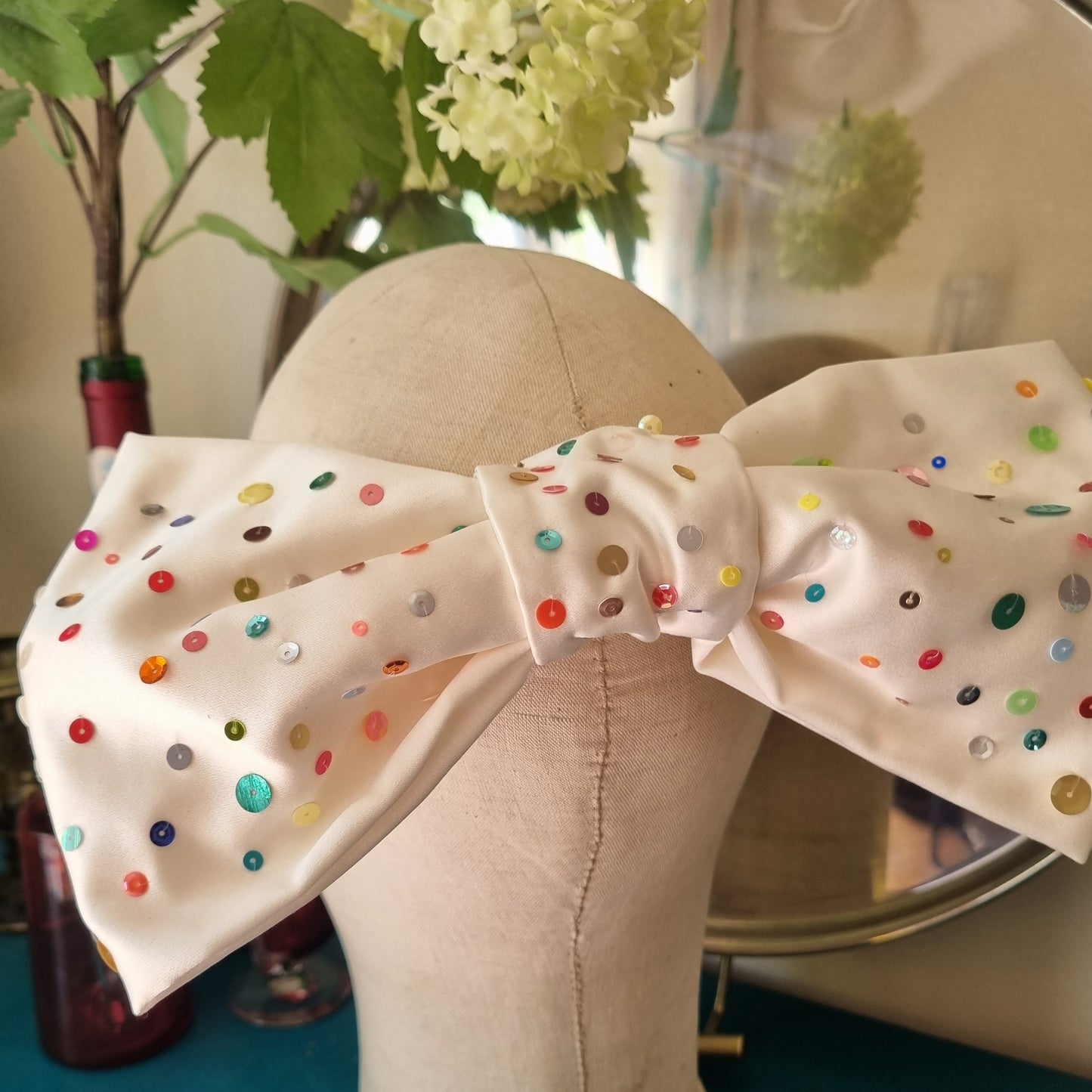 A large white silk bow with multi coloured sequin scattered all over