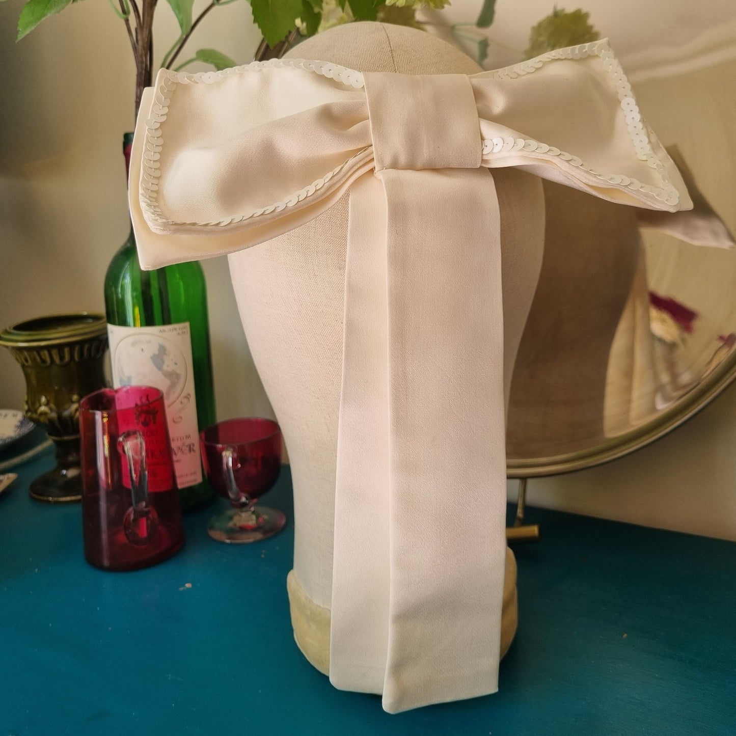 A white silk bow with an outline of white sequins on a head mannequin