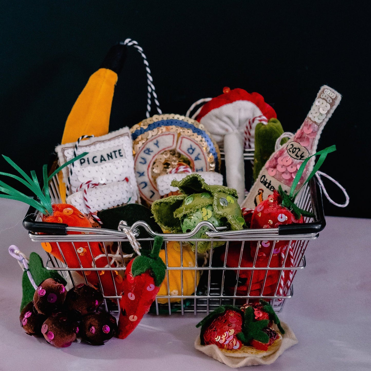 A small shopping basket filled with sequin ornaments of groceries