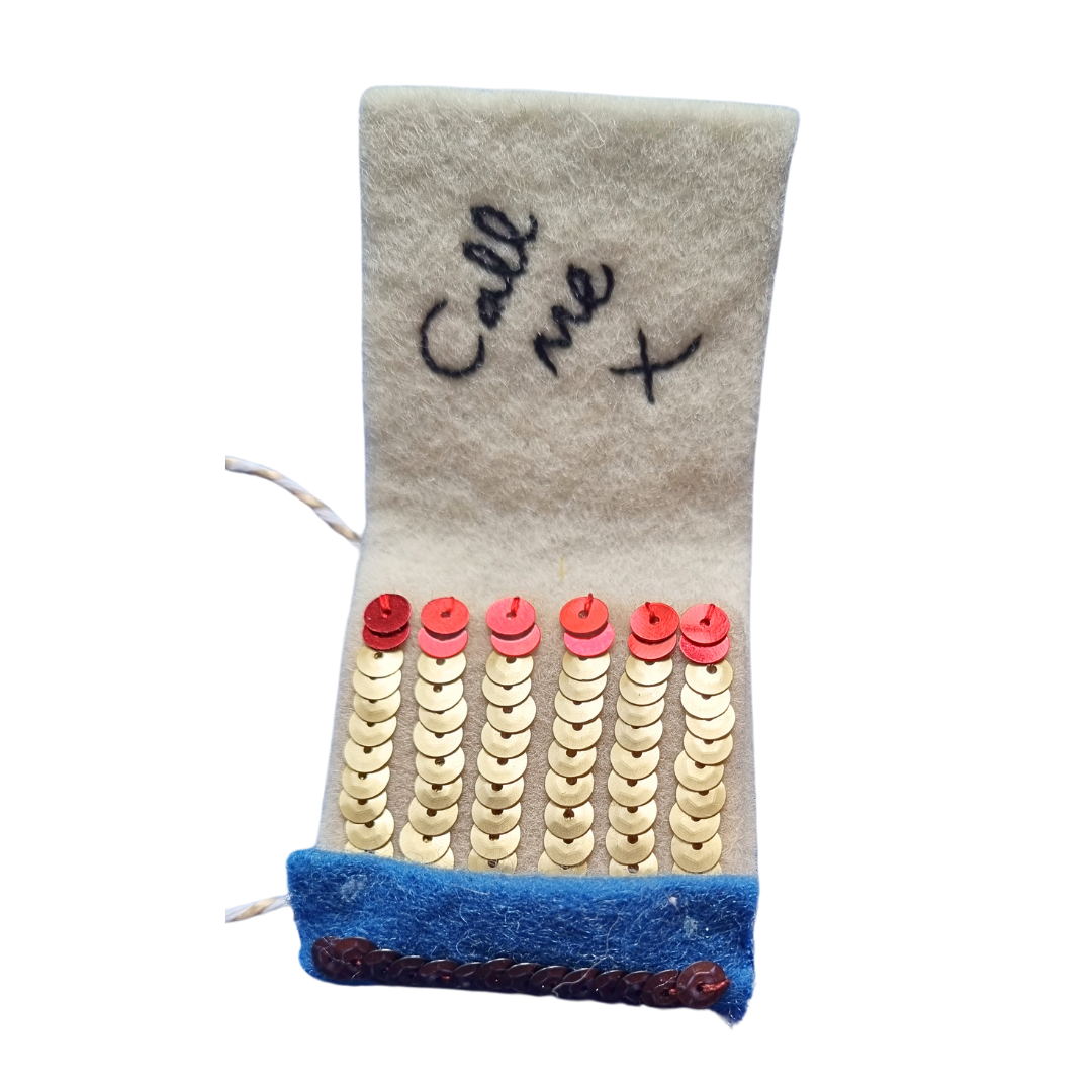An embroidered and sequinned open matchbook ornament
