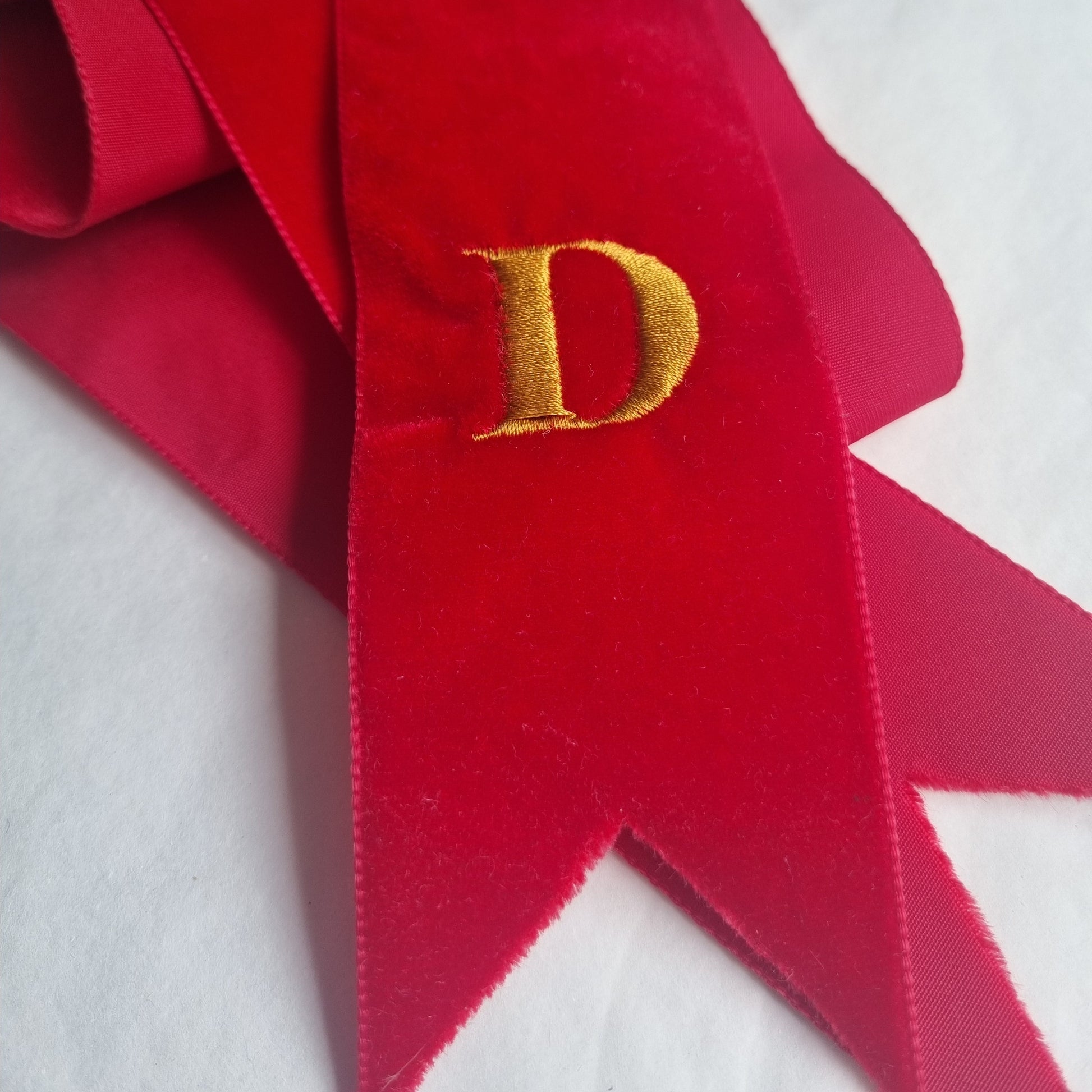 A red velvet ribbon with a golden D embroidered on it