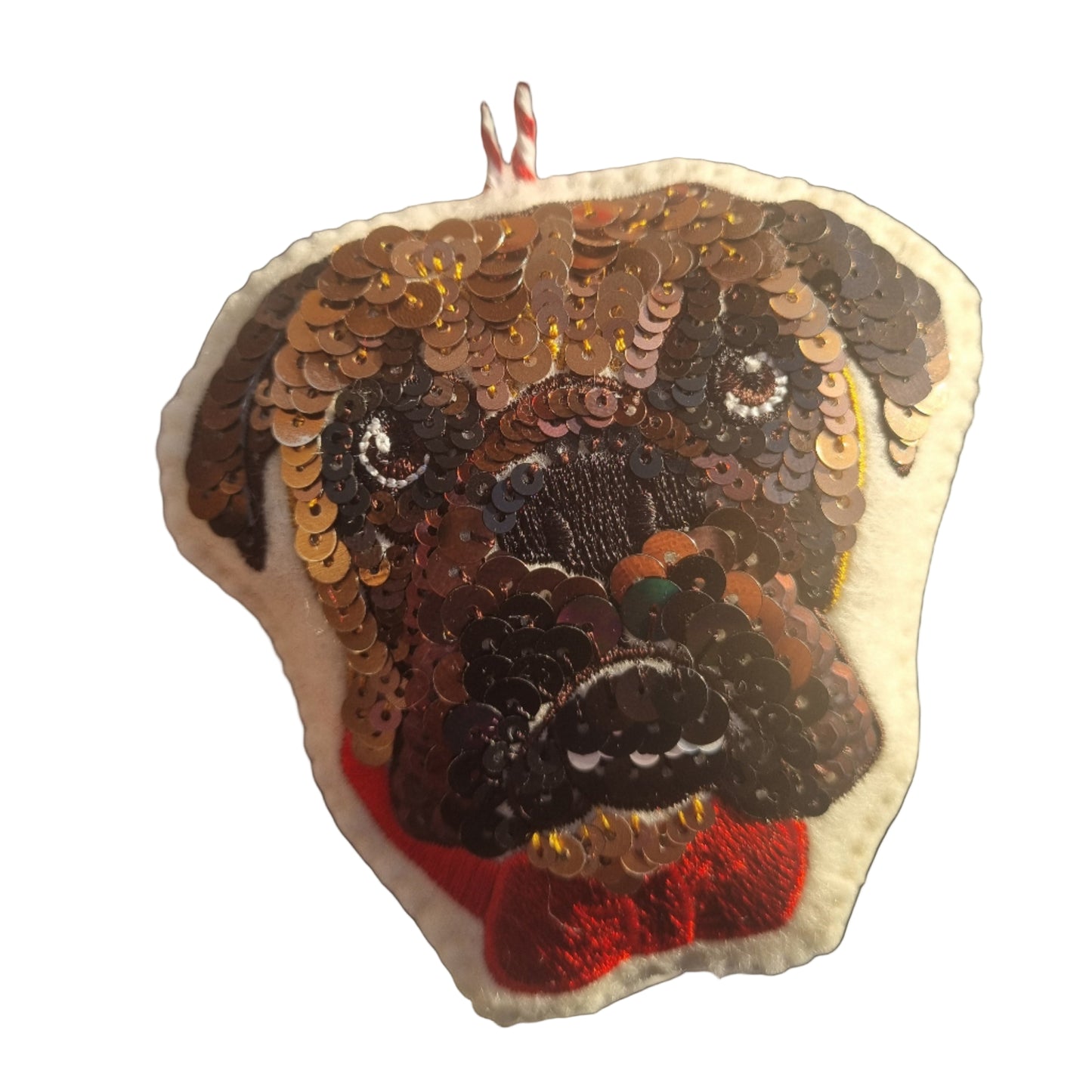 Sequined dog tree ornament with red bow on a light fabric background