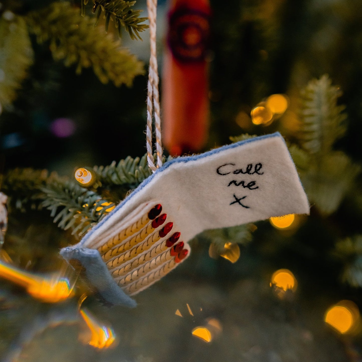 A matchbook embroidered and sequin ornament on a tree
