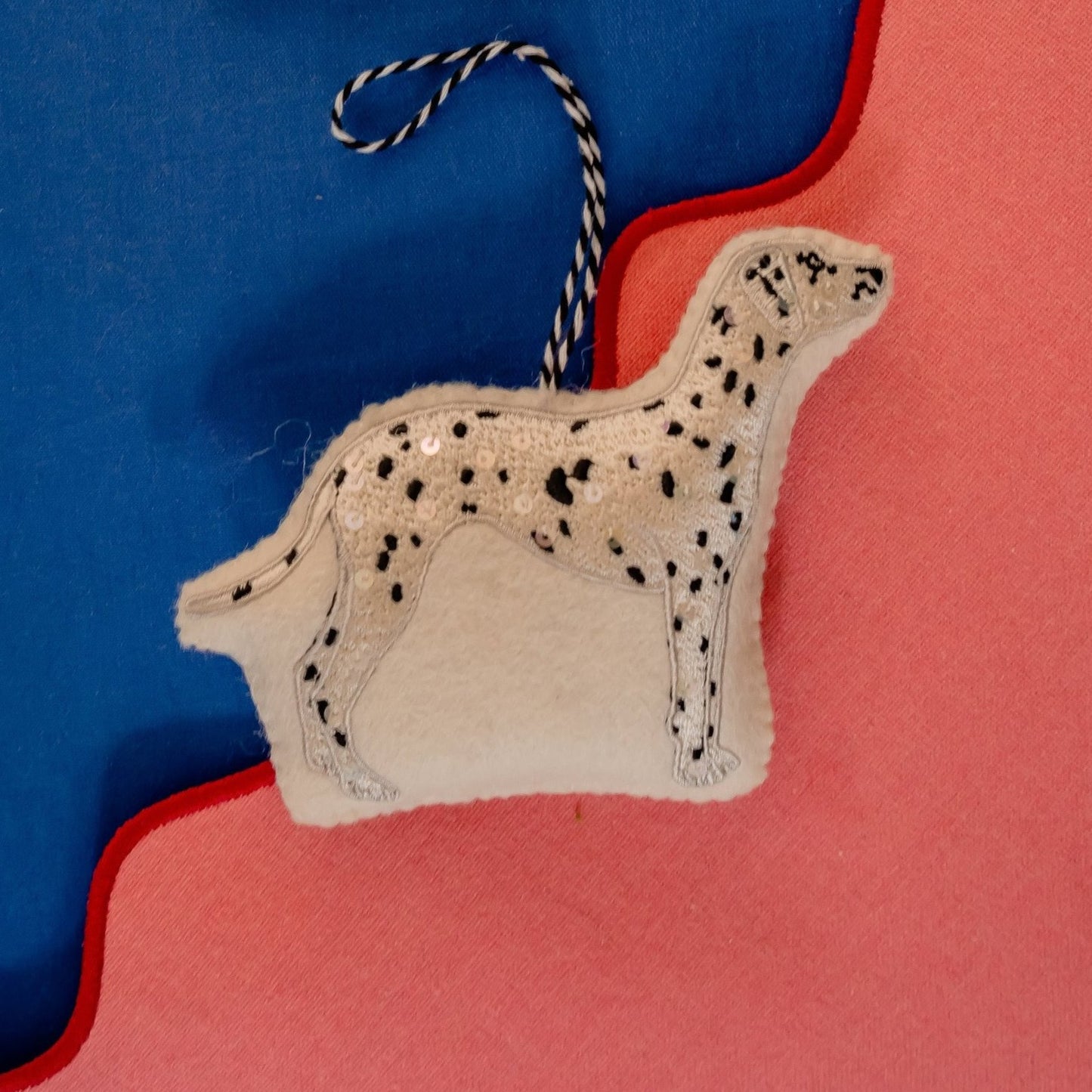 An embroidered and Sequinned Dalmatian ornament on A pink and Blue Background