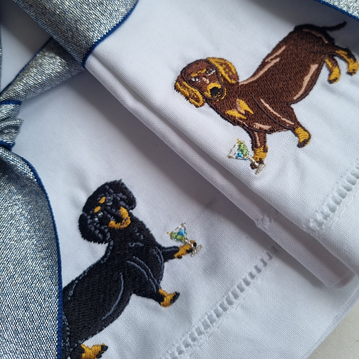 Two white napkins with a black and tan Dachshund and a Chocolate and tan Dachshund with martinis on each one