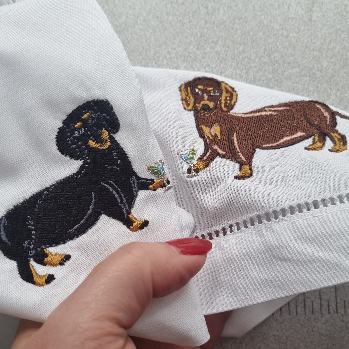 Kate's hand holding two napkins with Dachshunds embroidered on it