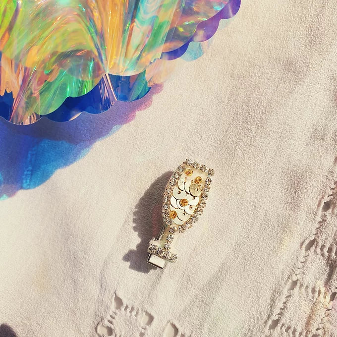 The Jo, Glass of Fizz Hair Clip, a small sequin champagne flute on a hairclip