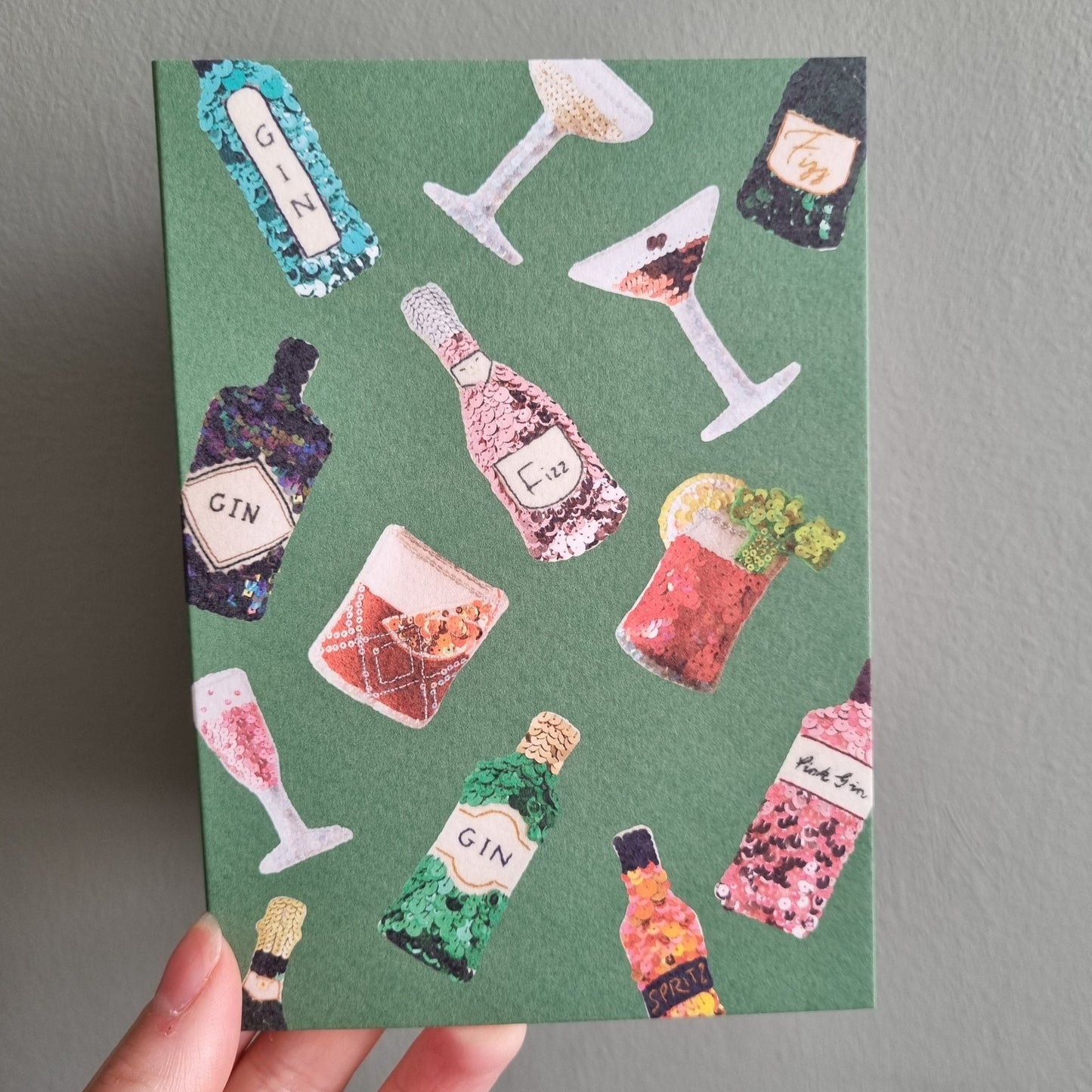Kate's hand holding a green card covered in all the favourite ornaments