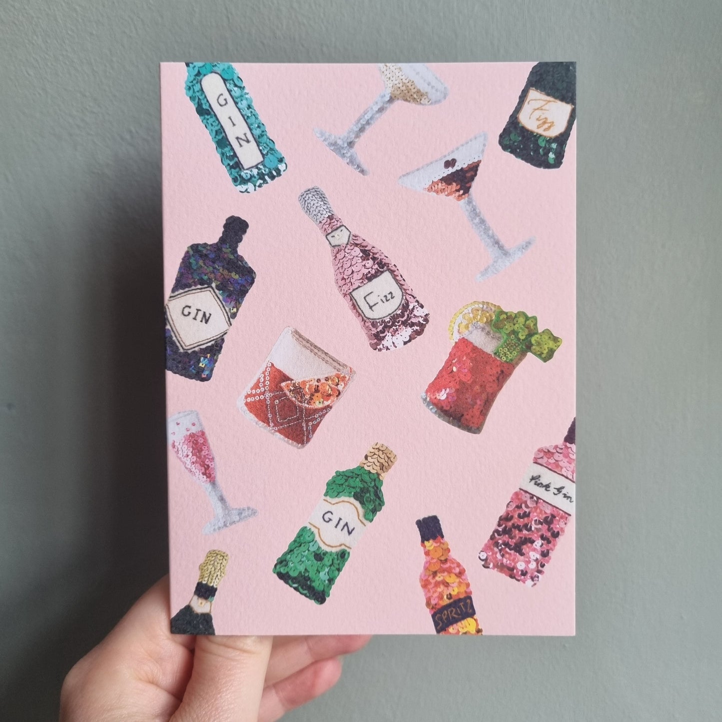Kate's hand holding a pale pink card covered in your favourite ornaments
