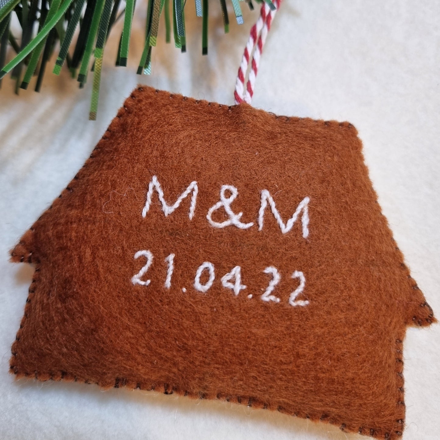 The reverse of a gingerbread ornament with M & M and 21.04.22 embroidered on it