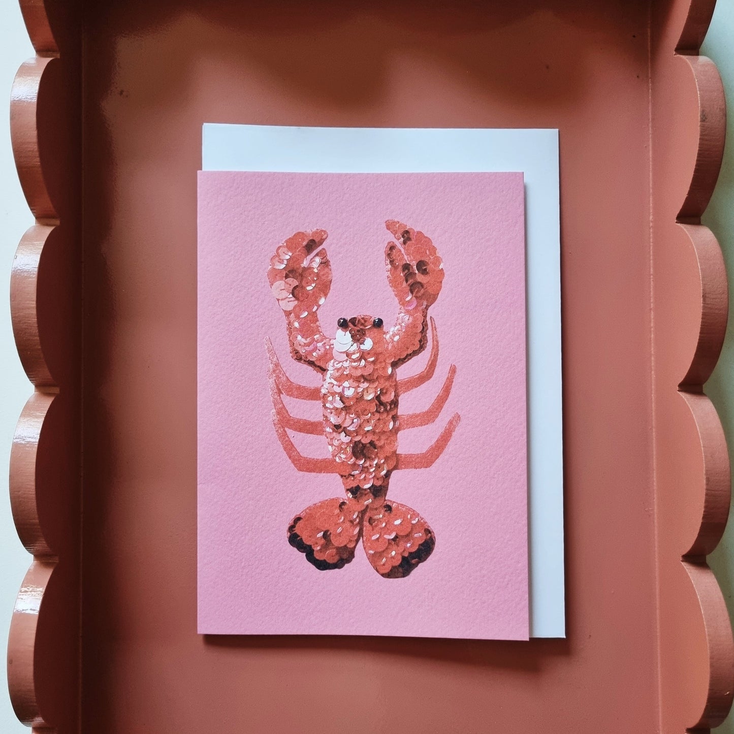 A pink card with the image of a sequinned lobster on it