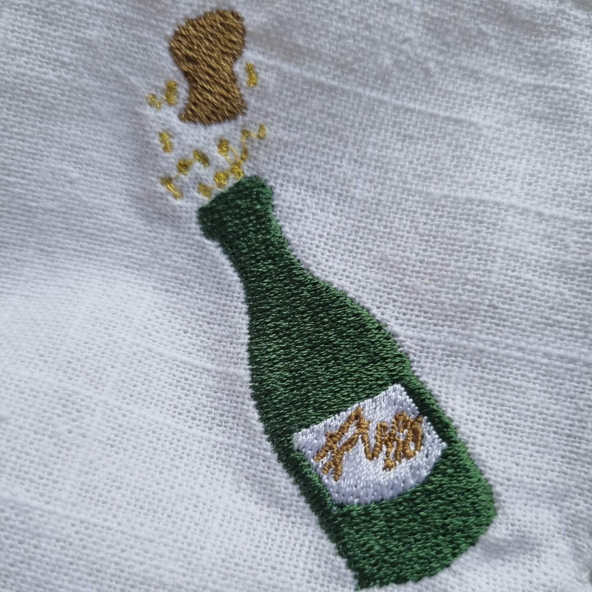 an embroidered champagne bottle on a white napkin