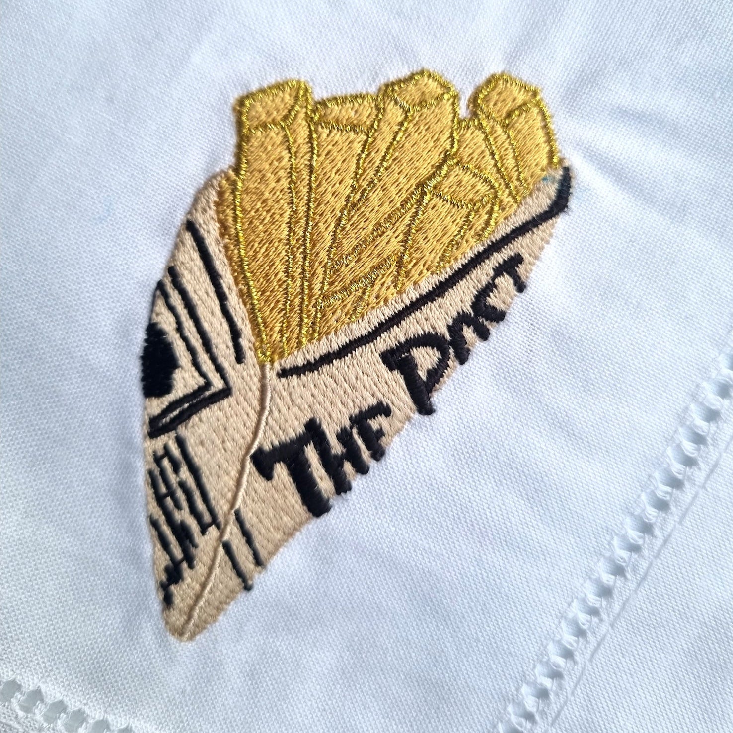An embroidered newspaper cone of chips on  white napkin