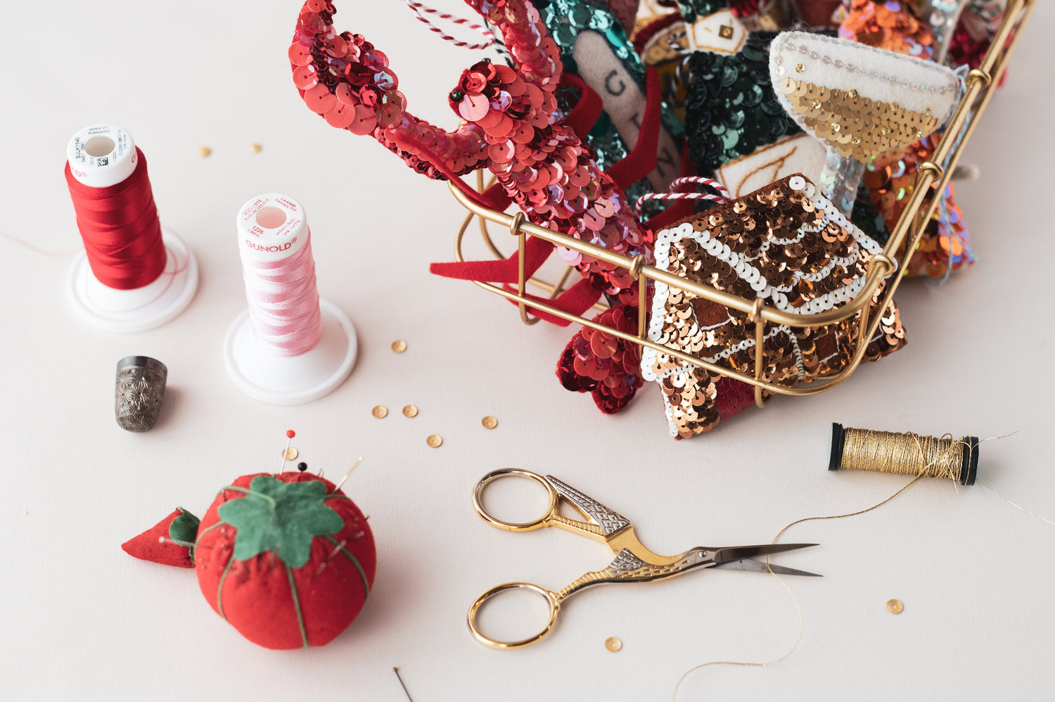 a collection of sequin ornaments including a lobster and gingerbread house on my desk. wit hthreads, needles and sequins scattered around