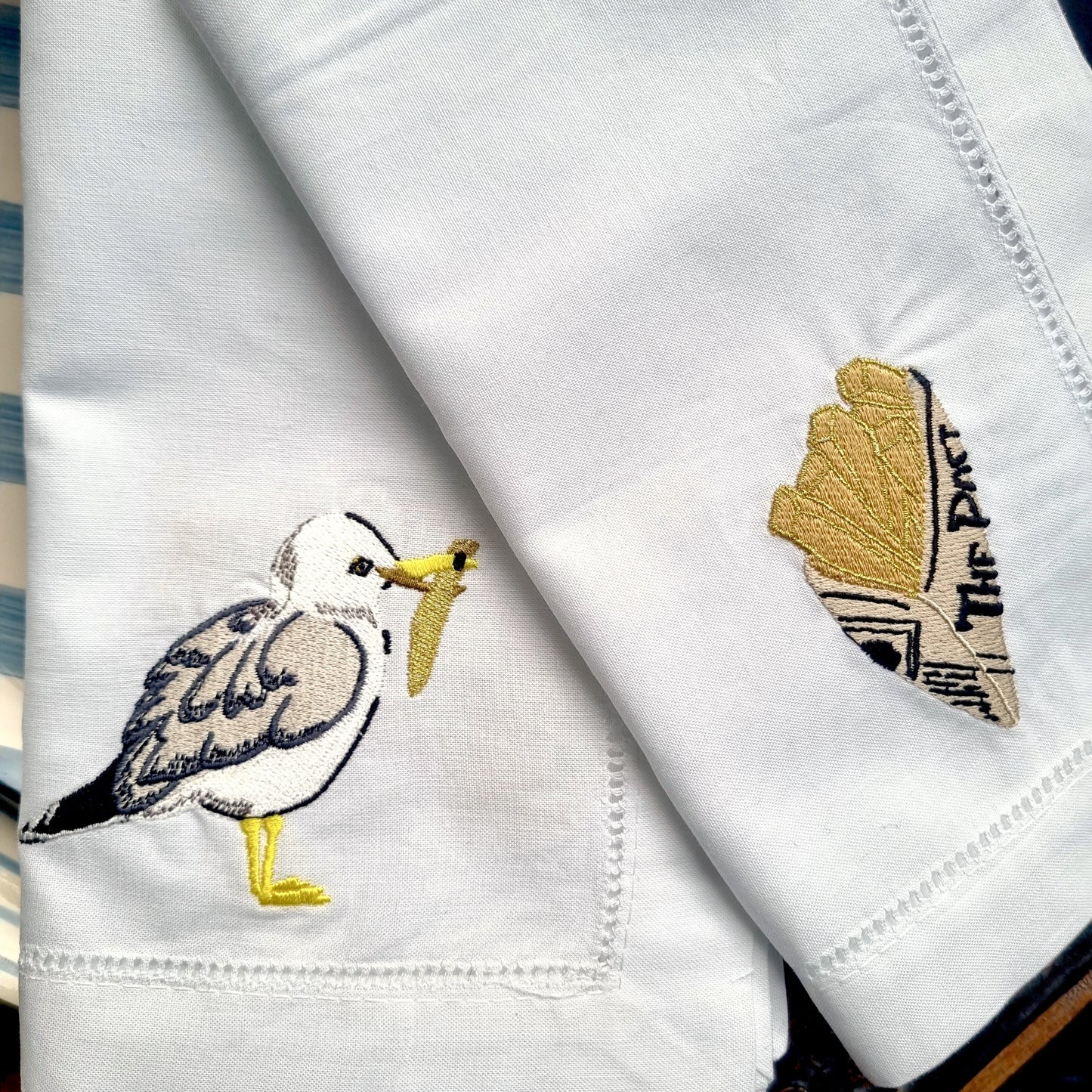 White napkin with embroidered seagull design on a wooden surface
