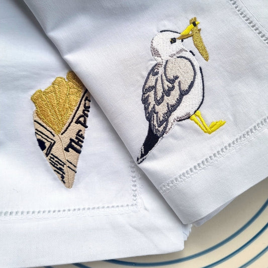 White napkin with embroidered seagull design on a light blue background