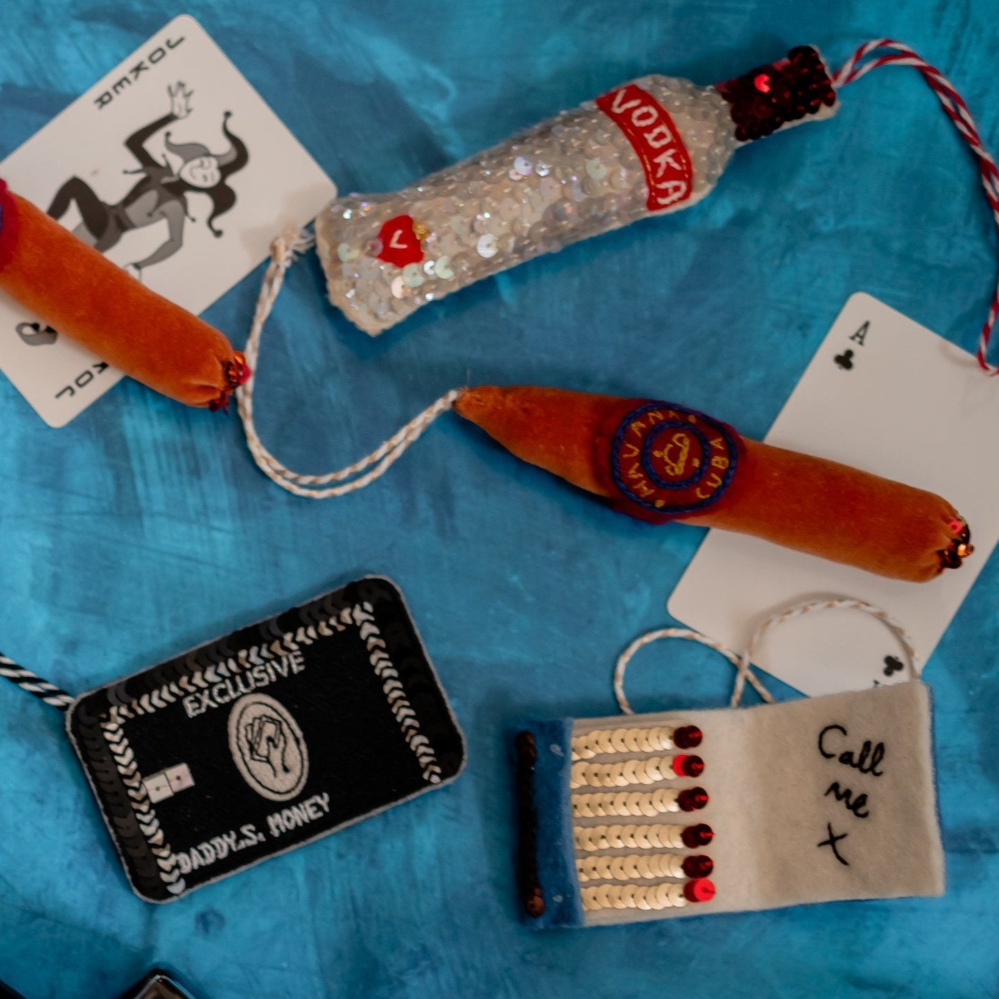 Sequinned ornaments including a cigar on a blue background