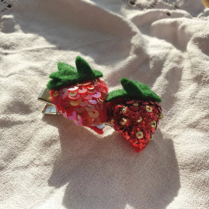 The Double Strawberry Hair Clip, two sequin strawberries, one a light red and one a metallic red on a metal hairclip