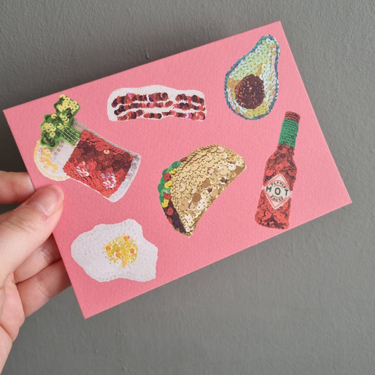 Kate's hand holding a pink card with popular brunch items taken from original sequin embroideries
