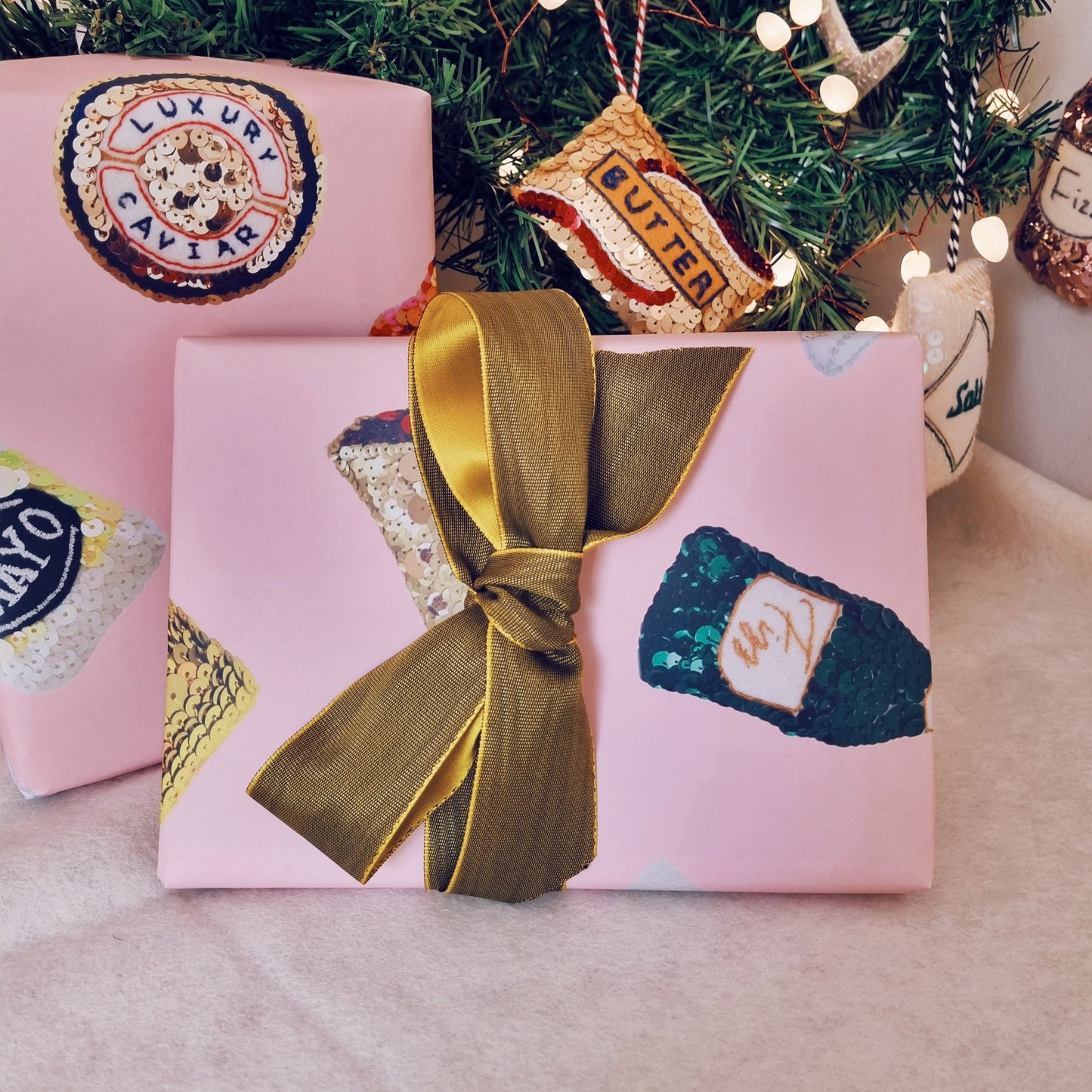 pink wrapping paper with sequin ornament images all over it wrapped up boxes under the tree