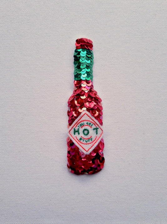 A high quality, artist quality print of a sequinned tabasco bottle that says you are hot stuff on the label