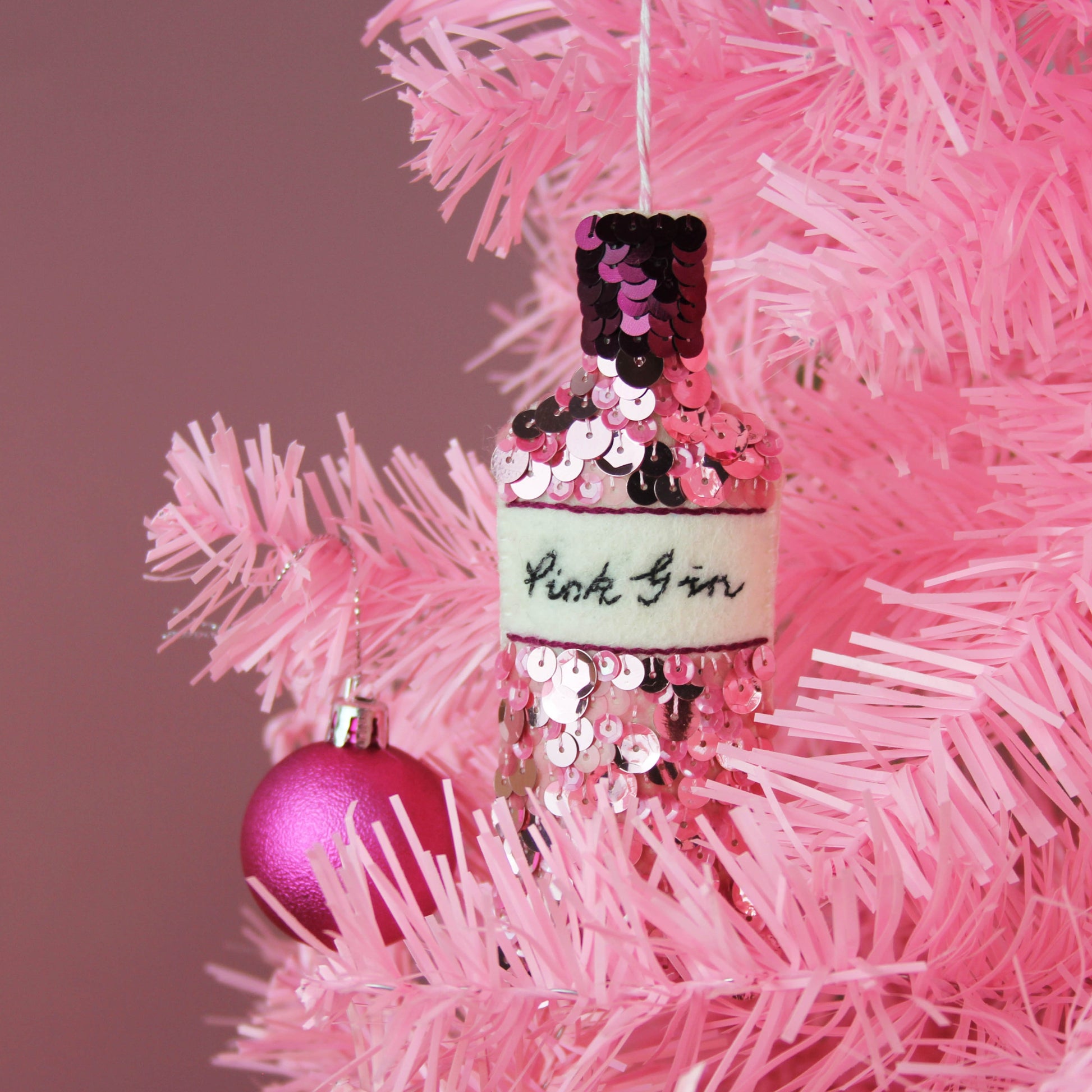 Pink Gin Sequin Hanging Decoration, hanging on a pink tree